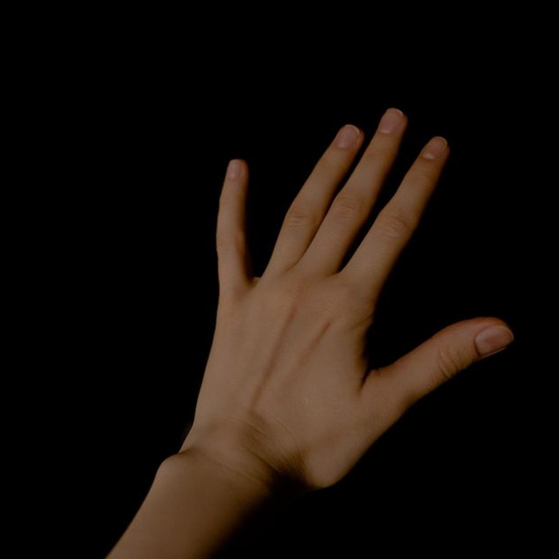 A detailed close-up of a human left hand against a dark background.